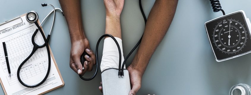 The arms of a doctor taking the blood pressure of a patient's arm