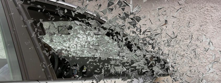 A car's front passenger window shattering as it crashes