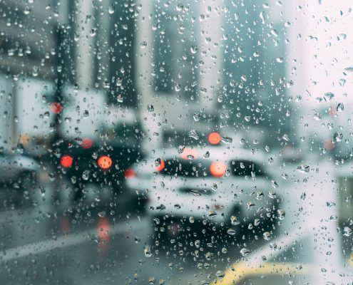 A close up of rain on a window with cars blurred in the background