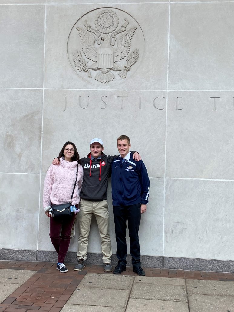 Three Oley Valley students standing under a seal and the word Justice