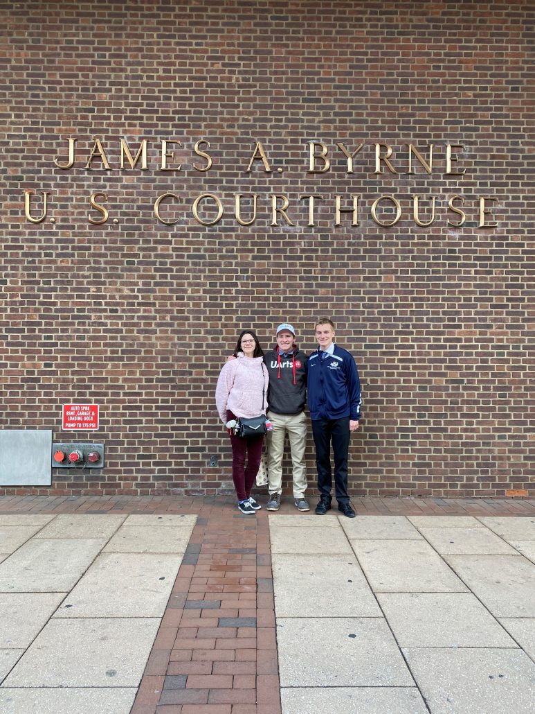 Three Oley Valley students standing under a James A. Byrne U.S. Courthouse sign