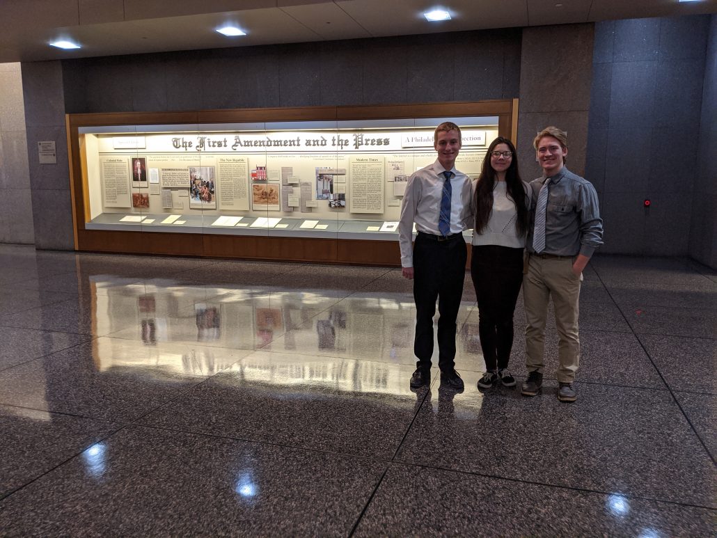 Three Oley Valley students standing together in front of a First Amendment display