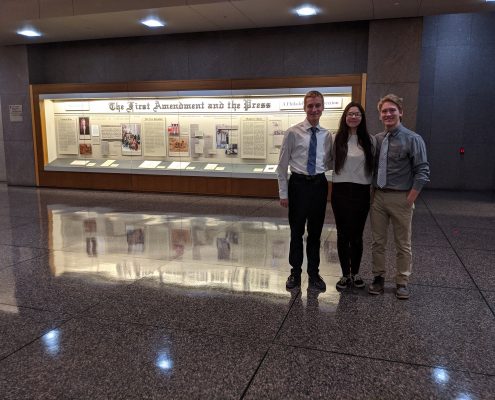 Three Oley Valley students standing together in front of a First Amendment display