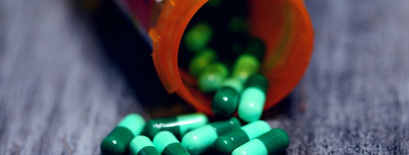 A pill bottle with green pills spilling out