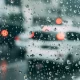 A close up of raindrops on a window with blurred cars in the background