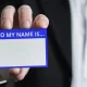 A person holding out a blank "Hello my name is..." tag