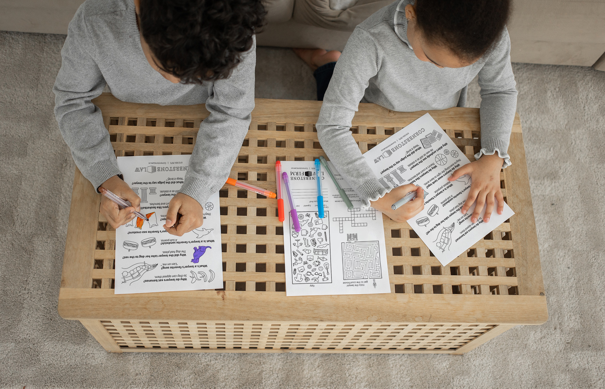 Two children coloring on Cornerstone Law Firm activity sheets