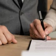 A photo of two people sitting at a table and signing a contract.
