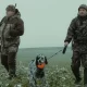Two hunters and their dog hunting on a winter morning