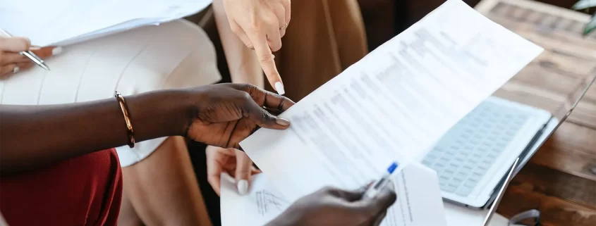 A woman's hand pointing to a document held by another woman