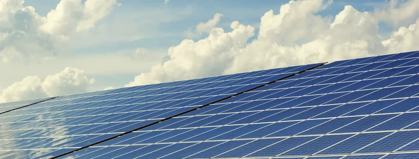 A photo of solar panels under a blue sky.