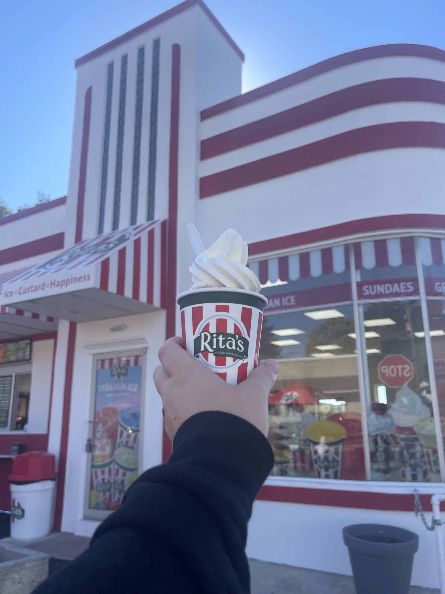 A hand holding a cup of vanilla custard outside of Rita's of Hamburg