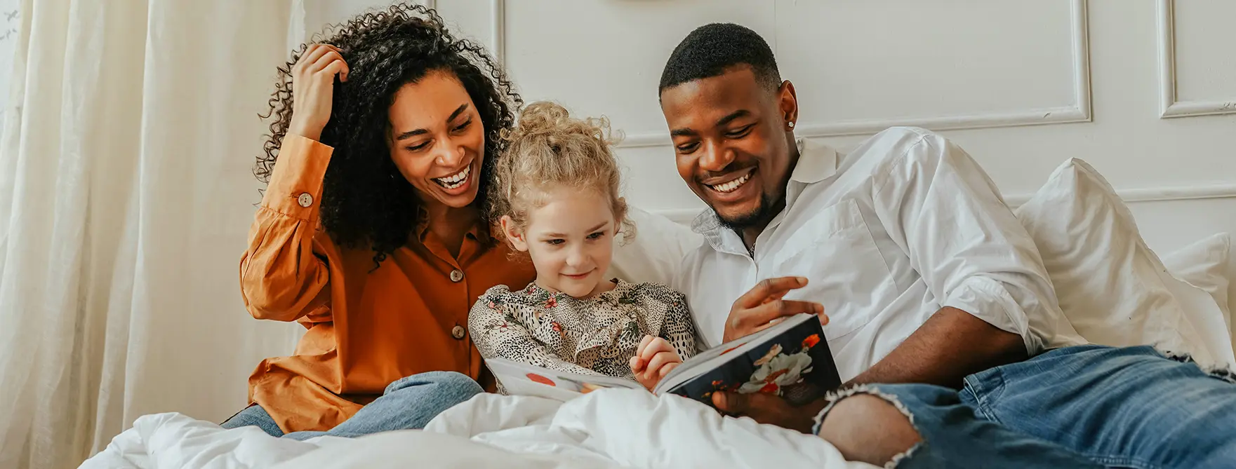 A mother and father reading a story to their adopted daughter