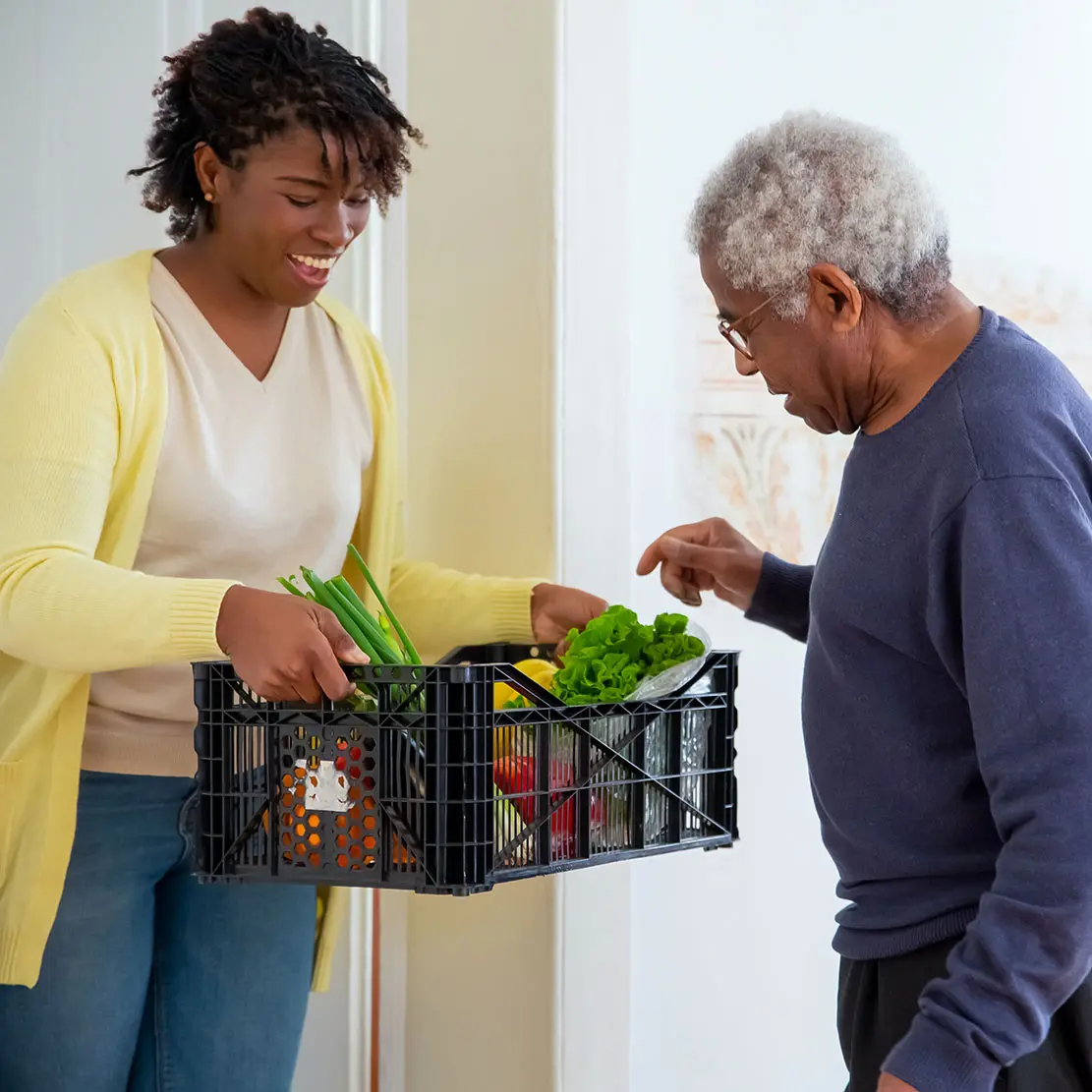 An adult daughter handing vegetables to her adoptive father