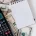 A calculator, notepad, and pen resting on a pile of cash