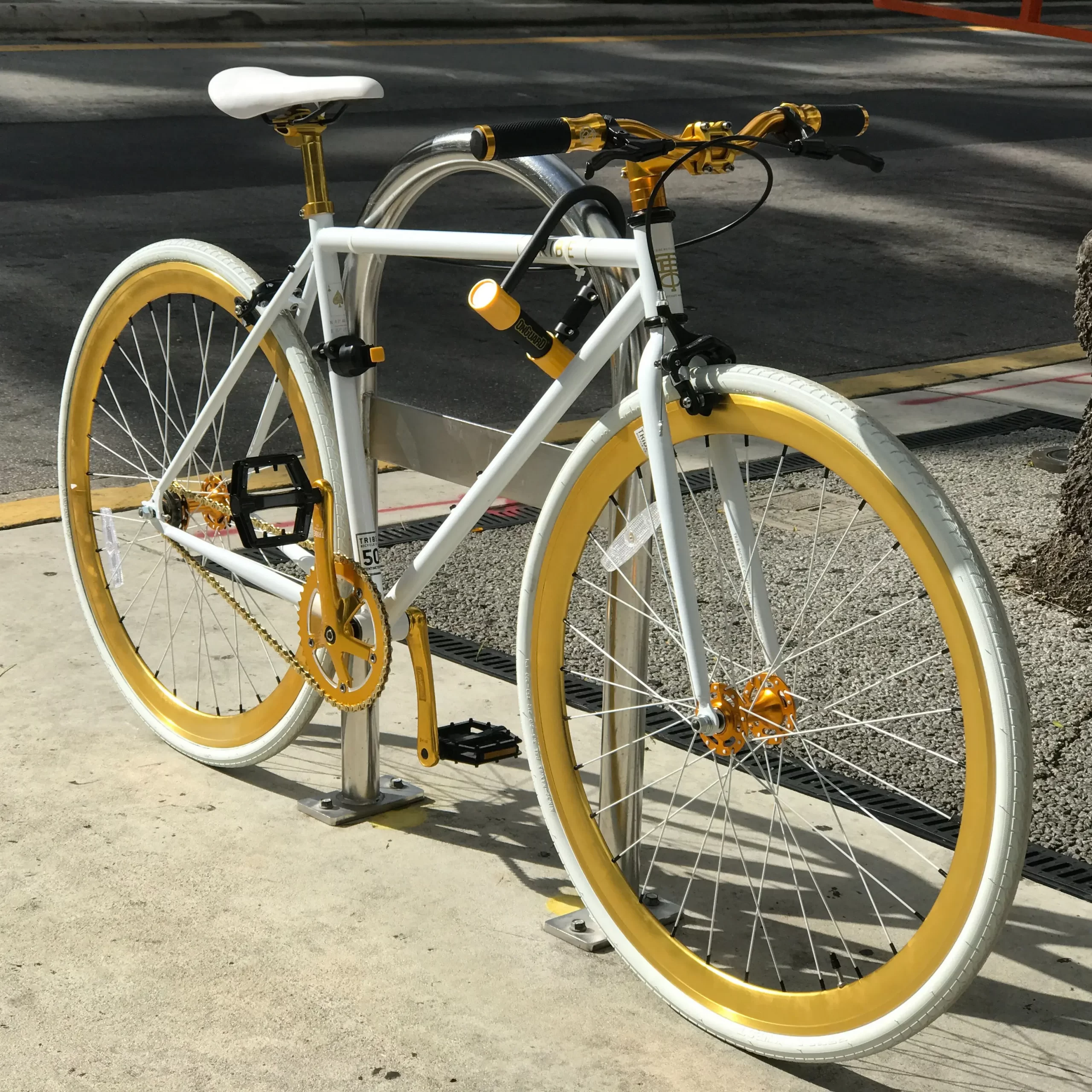 A yellow bicycle locked to a bike rack.