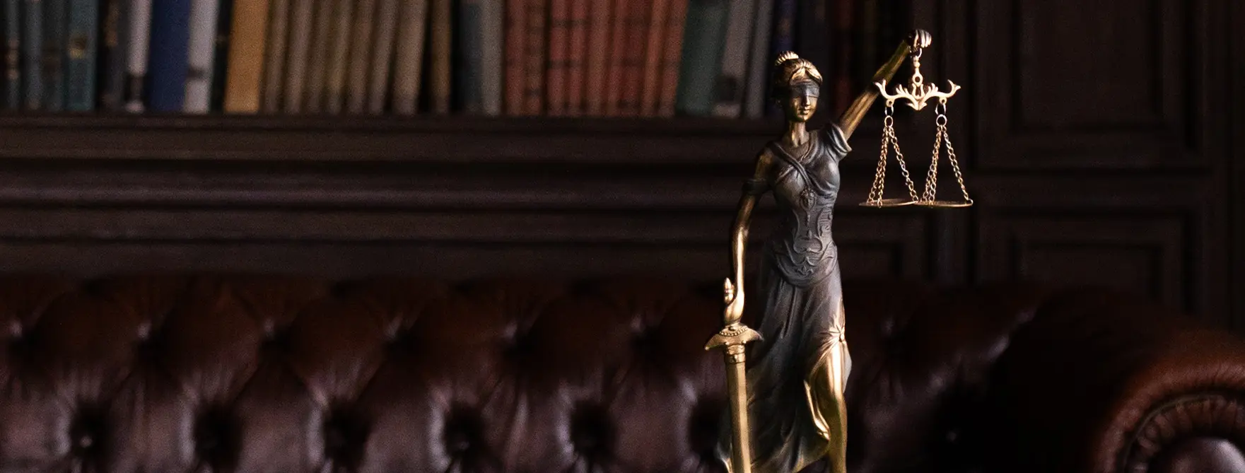A small statue of Lady Justice in front of a bookshelf