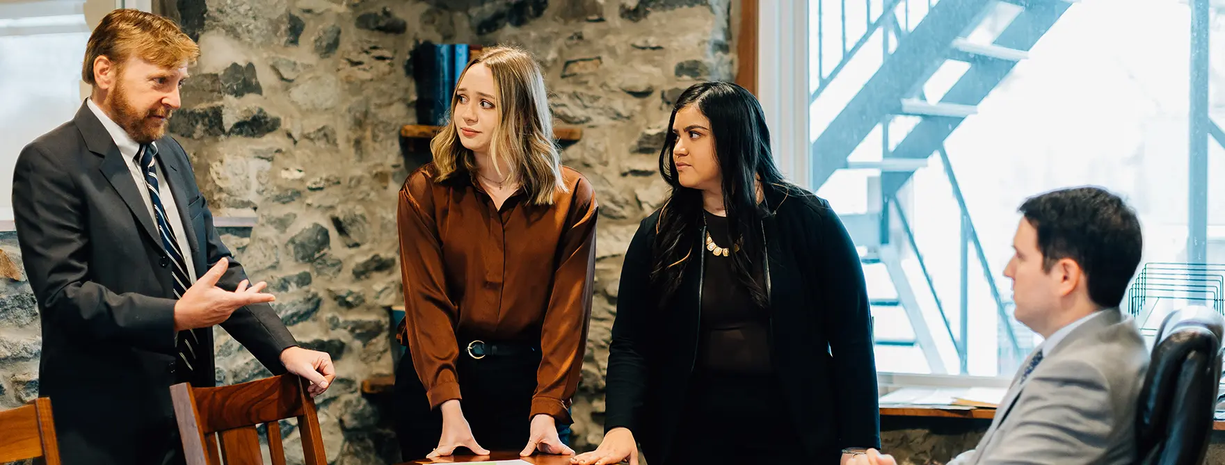 A Cornerstone paralegal explaining something to two other Cornerstone paralegals and a Cornerstone attorney.