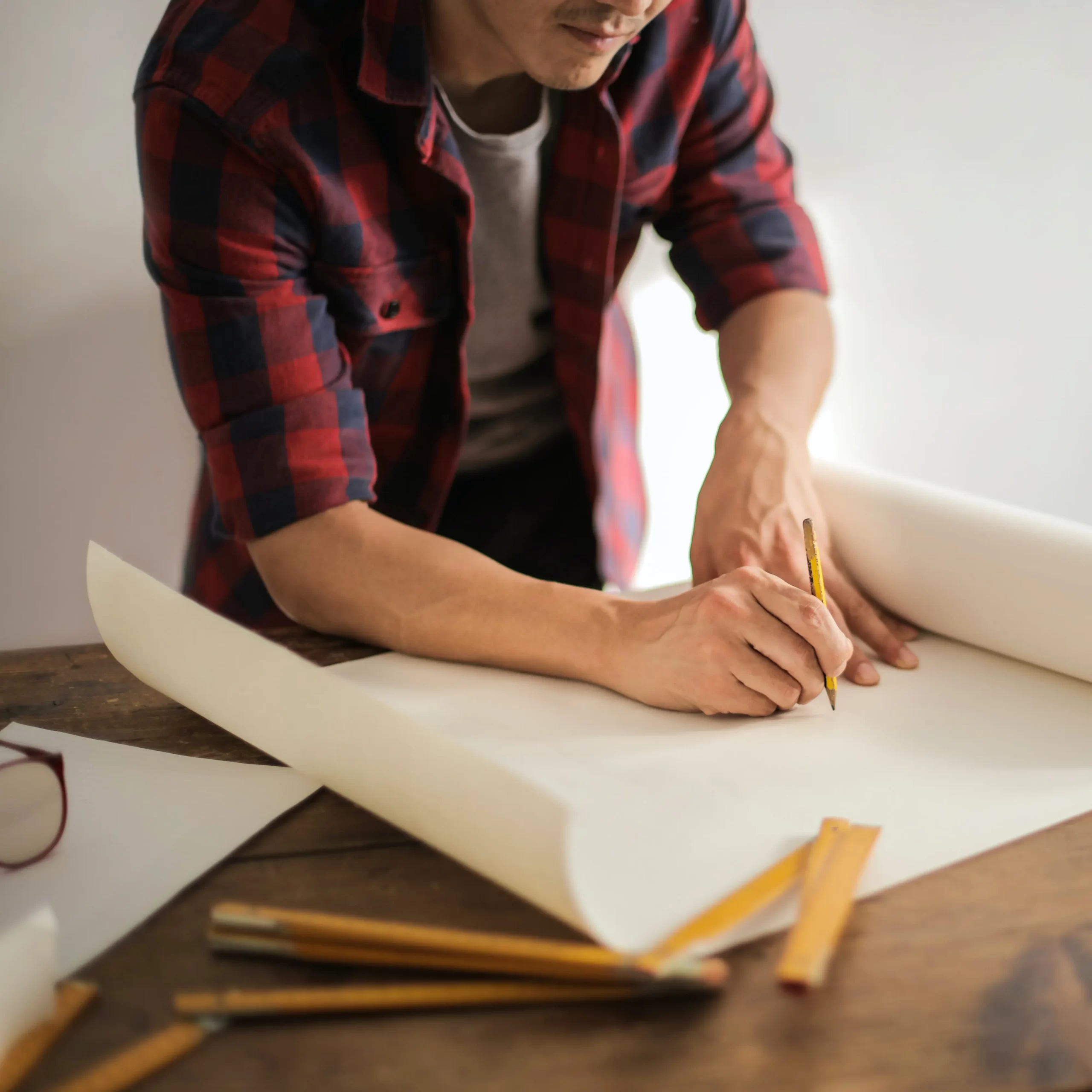 A contractor drawing plans on a large sheet of paper