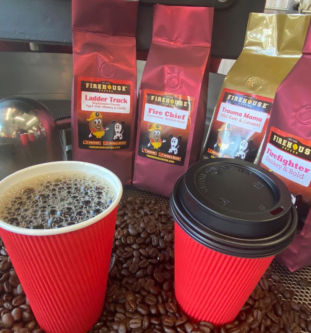 Some red coffee cups with bags of Firehouse Coffee beans in the background