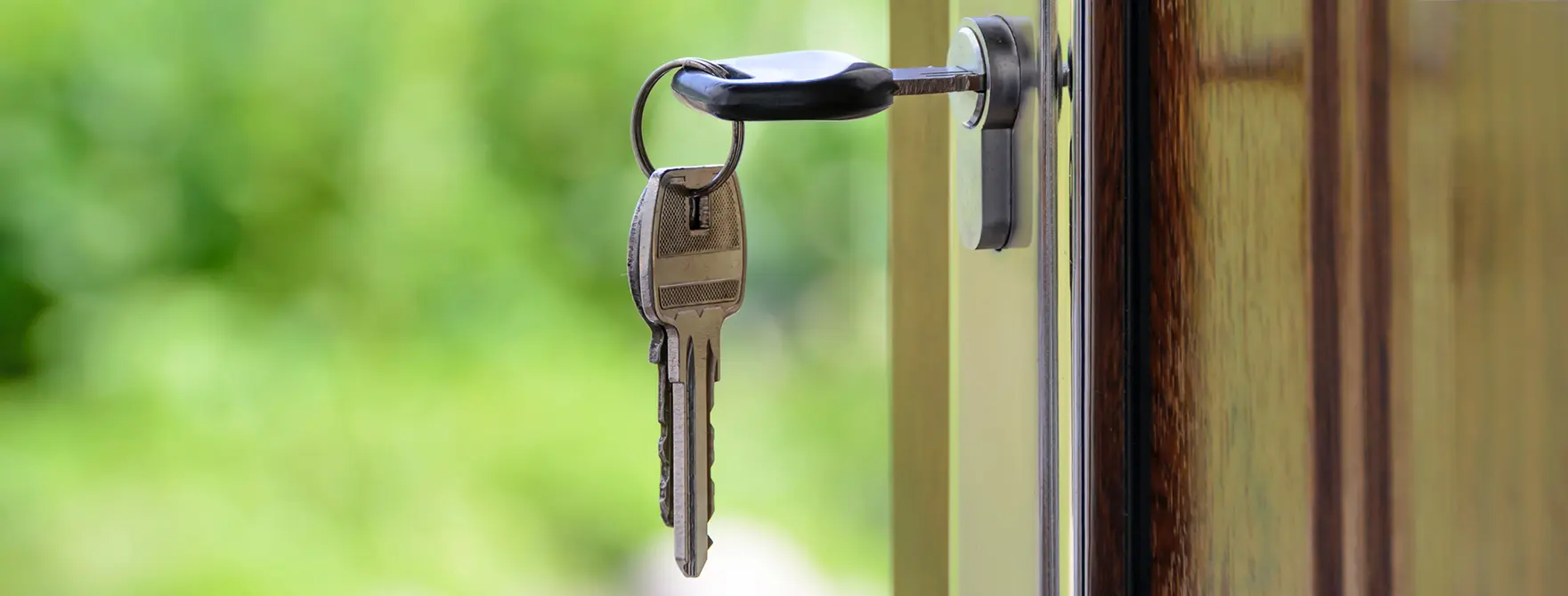 A key inserted into a front door with two other keys hanging off of it's keychain