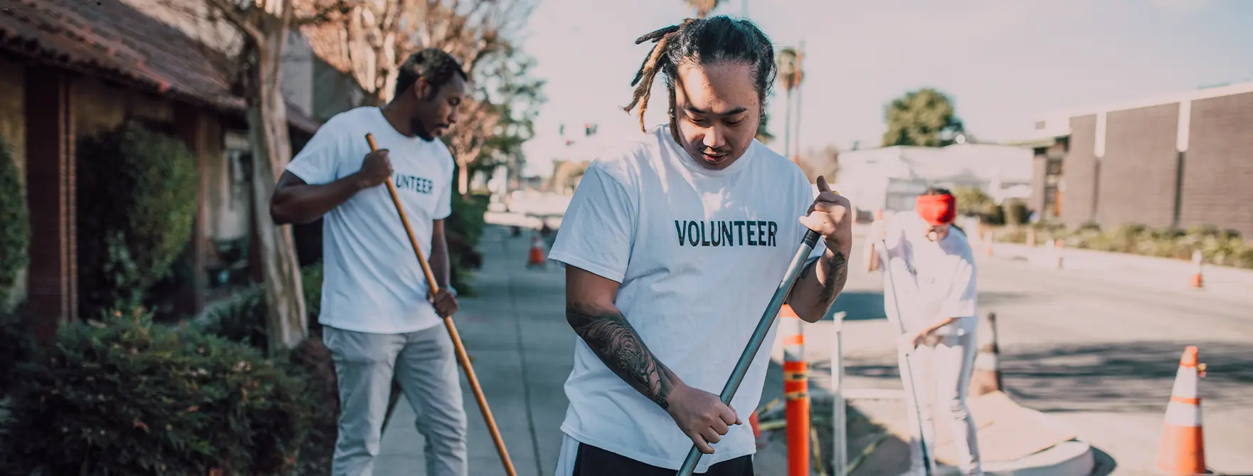 A group of 3 nonprofit volunteers cleaning a sidewalk.