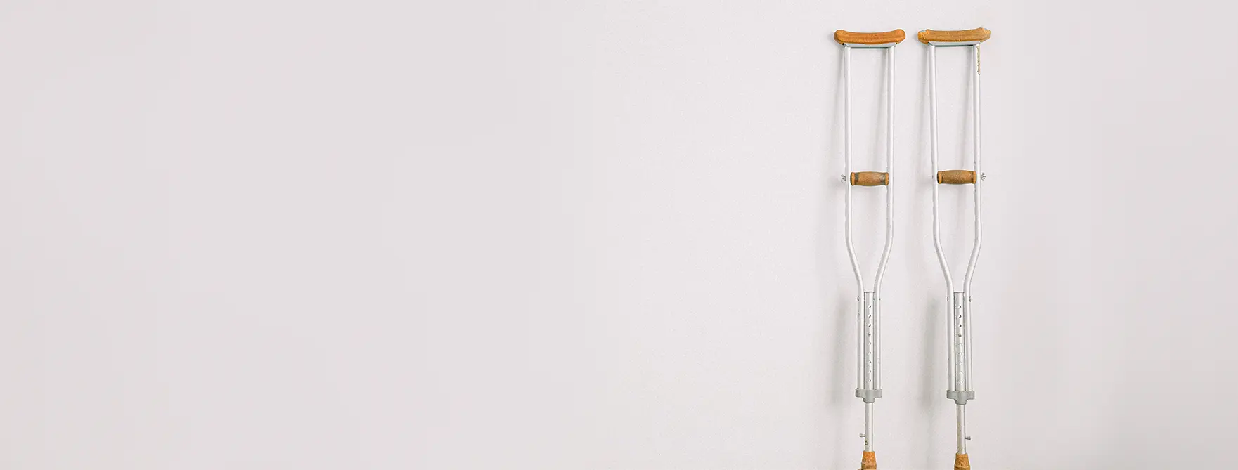 A pair of crutches leaning against a white wall.