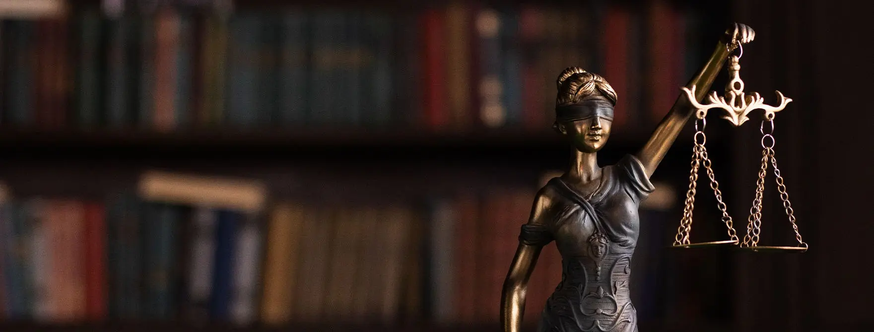 A Lady Justice statue in front of a bookshelf