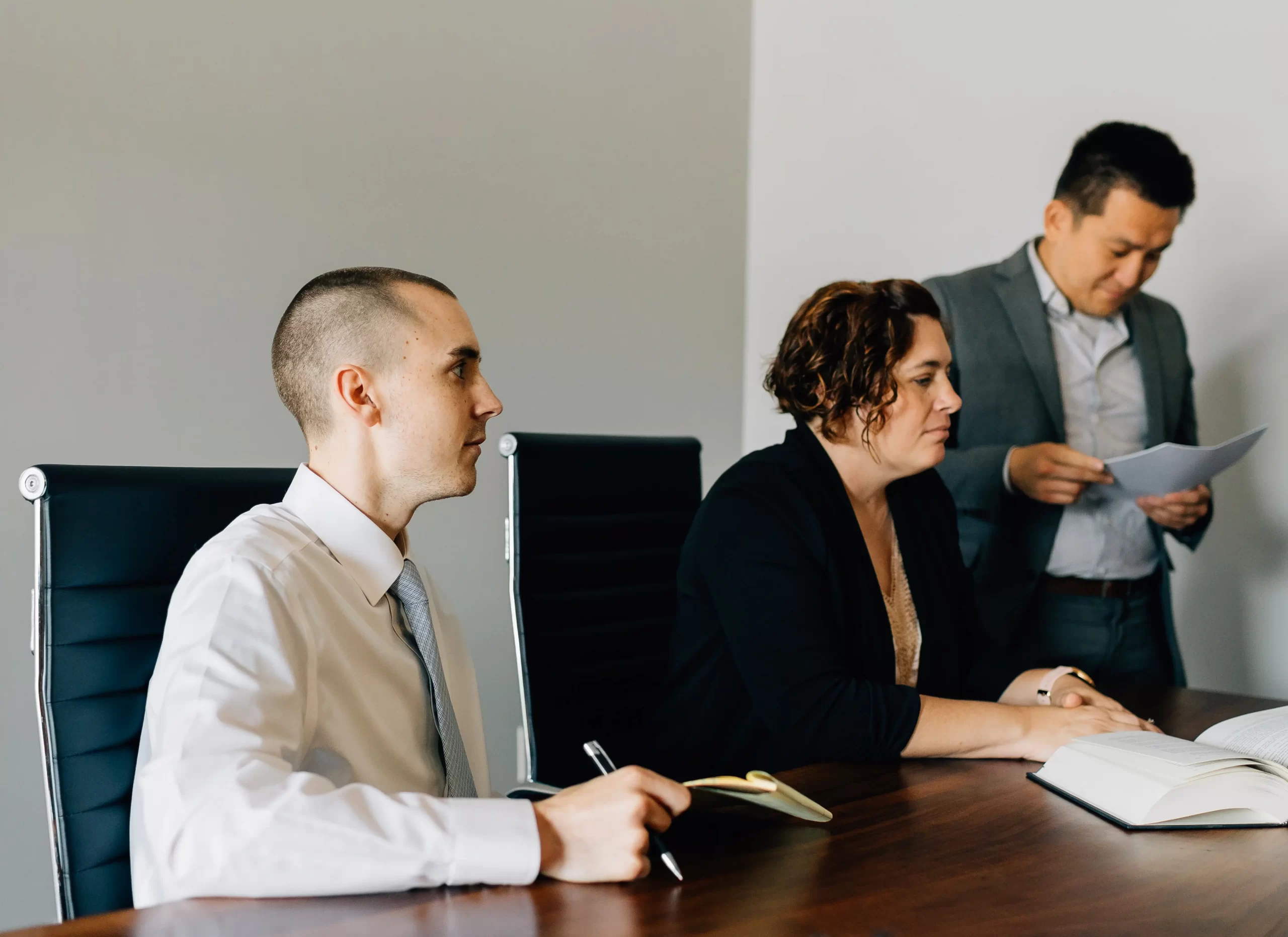 Two Cornerstone paralegals and an attorney around a conference table, having a meeting.