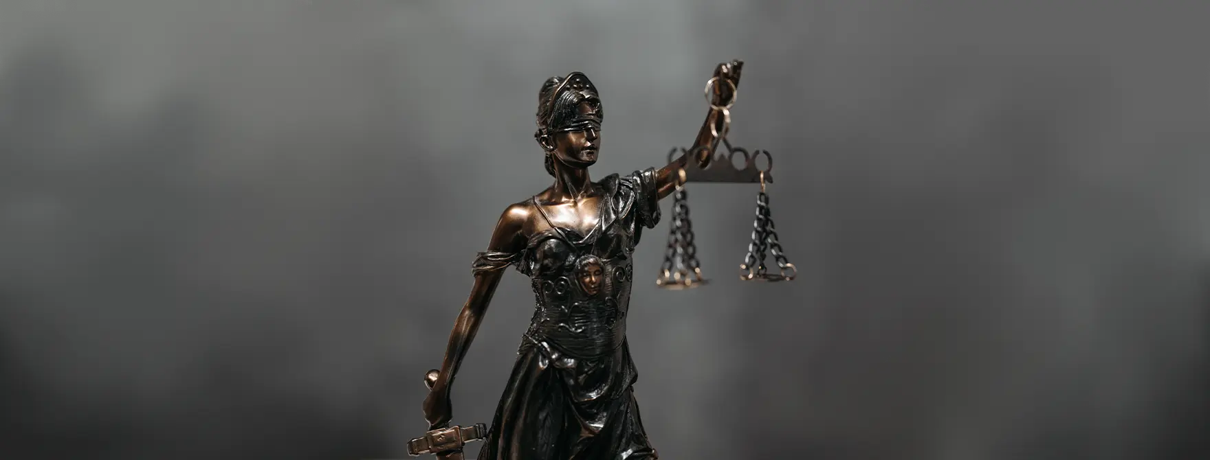 A statue of Lady Justice in front of a gray background.