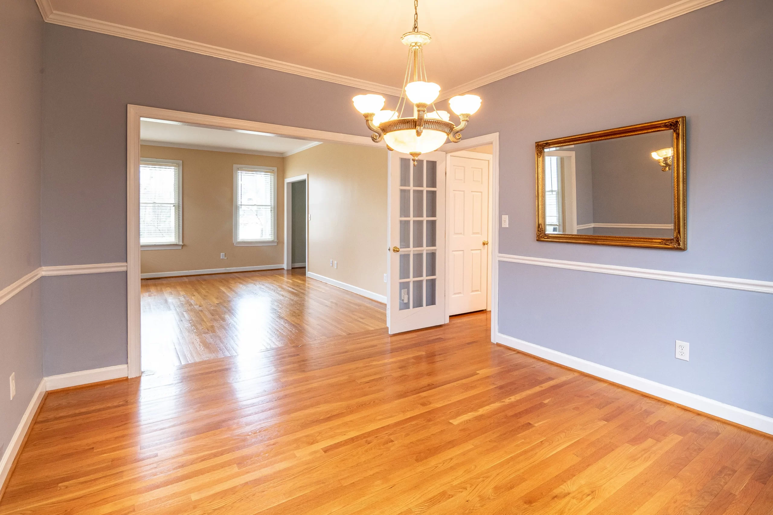 The inside of an empty, blue dining room with an ornate light fixture hanging from the ceiling.