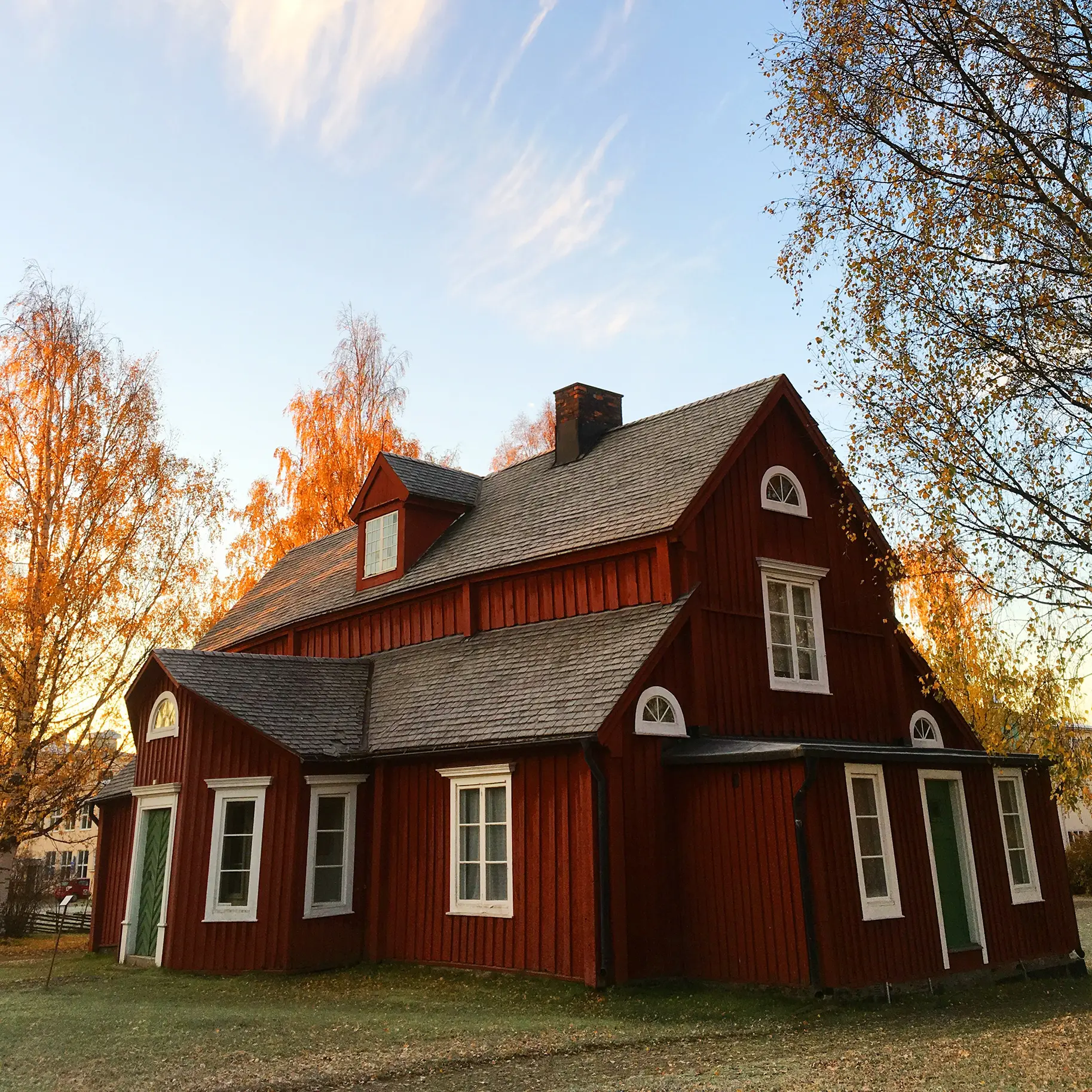 A picture of a red barn-style house on a sunny fall day.