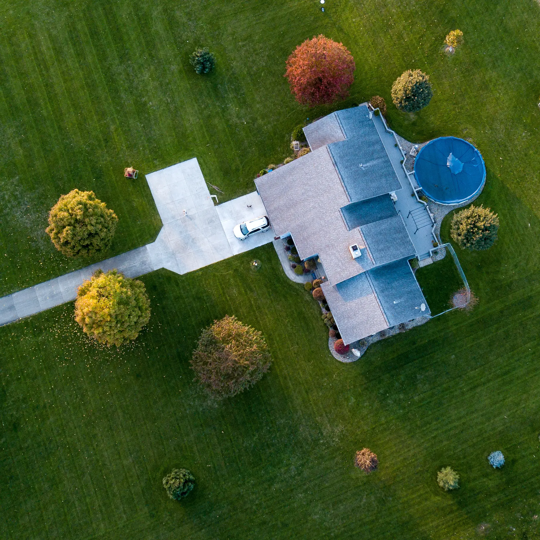 An arial shot of a house with a driveway and some landscaping.