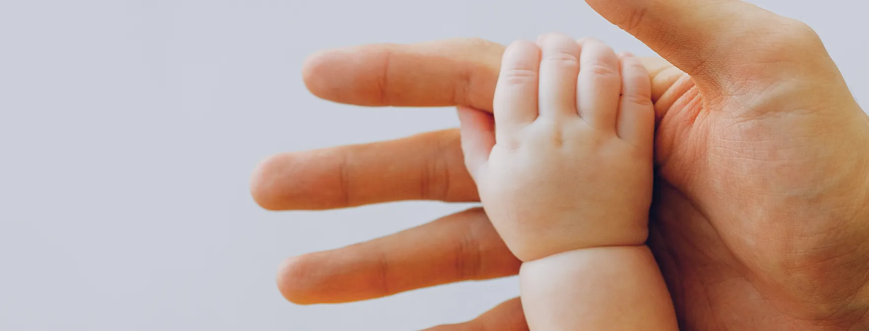 A parent holding a baby's hand