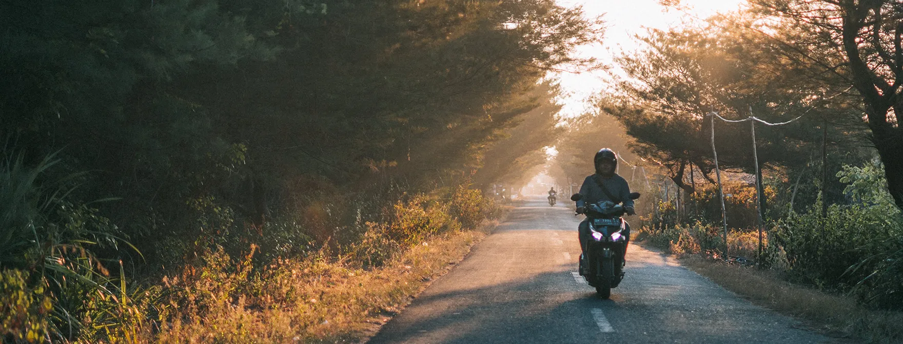 A motorcyclist driving on a road at sunset