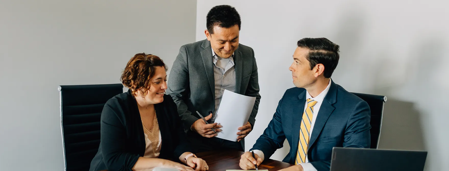 Two Cornerstone staff speaking with a Cornerstone attorney at a trust meeting.