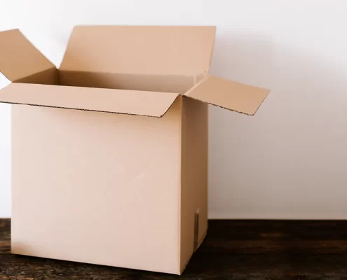 An empty moving box with a roll of packing tape and a pair of scissors next to it.
