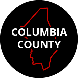 The words "Columbia County" in a black circle with red outline of the county behind it. The image links to a page listing the county's Magisterial District Courts.