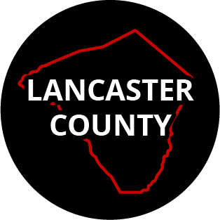 The words "Lancaster County" in a black circle with red outline of the county behind it. The image links to a page listing the county's Magisterial District Courts.