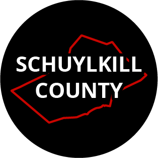 The words "Schuylkill County" in a black circle with red outline of the county behind it. The image links to a page listing the county's Magisterial District Courts.
