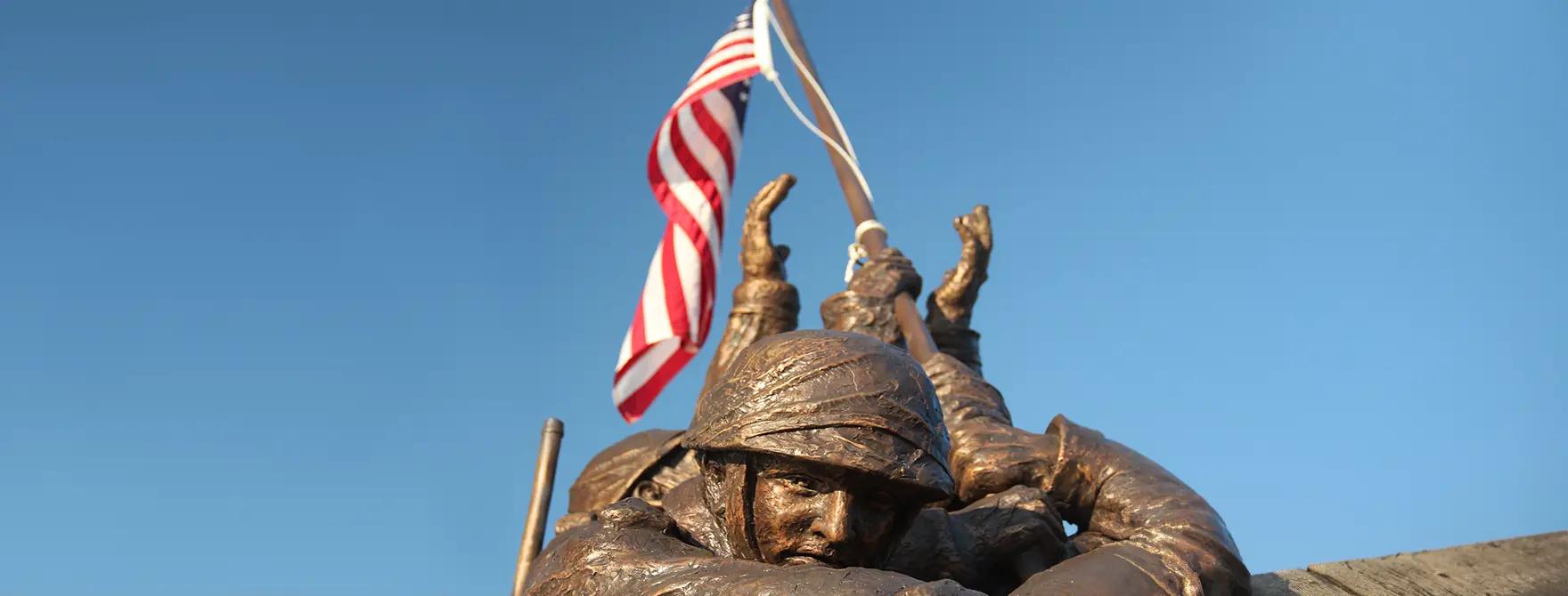 The top of a statue of soldiers holding an American flag