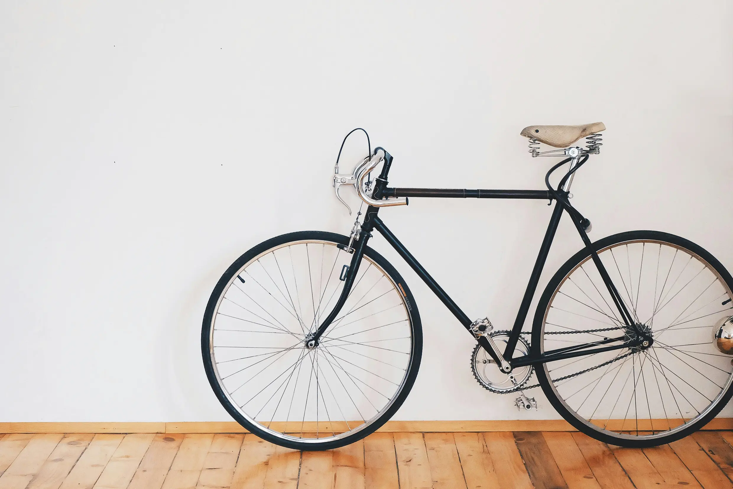 A black bicycle leaning against a white wall