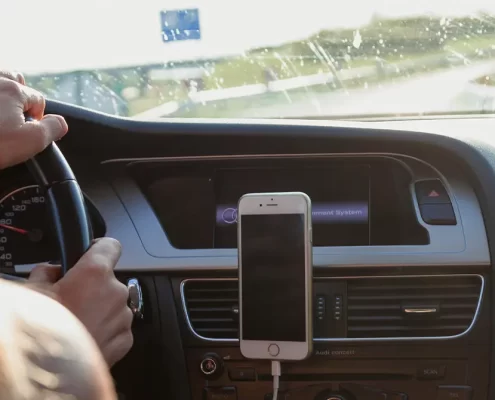 A woman driving with a cell phone mounted to her dashboard.