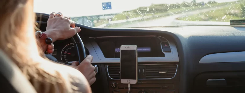 A woman driving with a cell phone mounted to her dashboard.