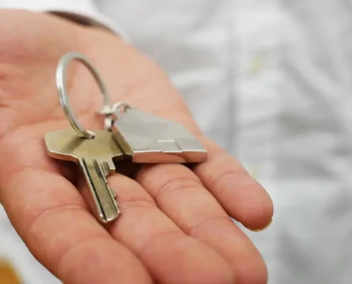 An outstretched hand holding a house key