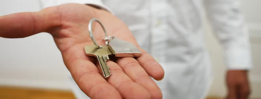 An outstretched hand holding a house key