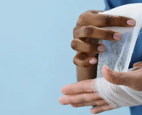 A doctor's hands wrapping an injured patient's hand with gauze