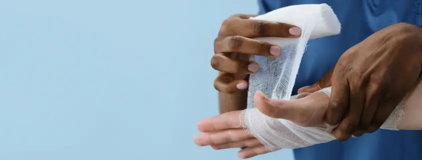 A doctor's hands wrapping an injured patient's hand with gauze