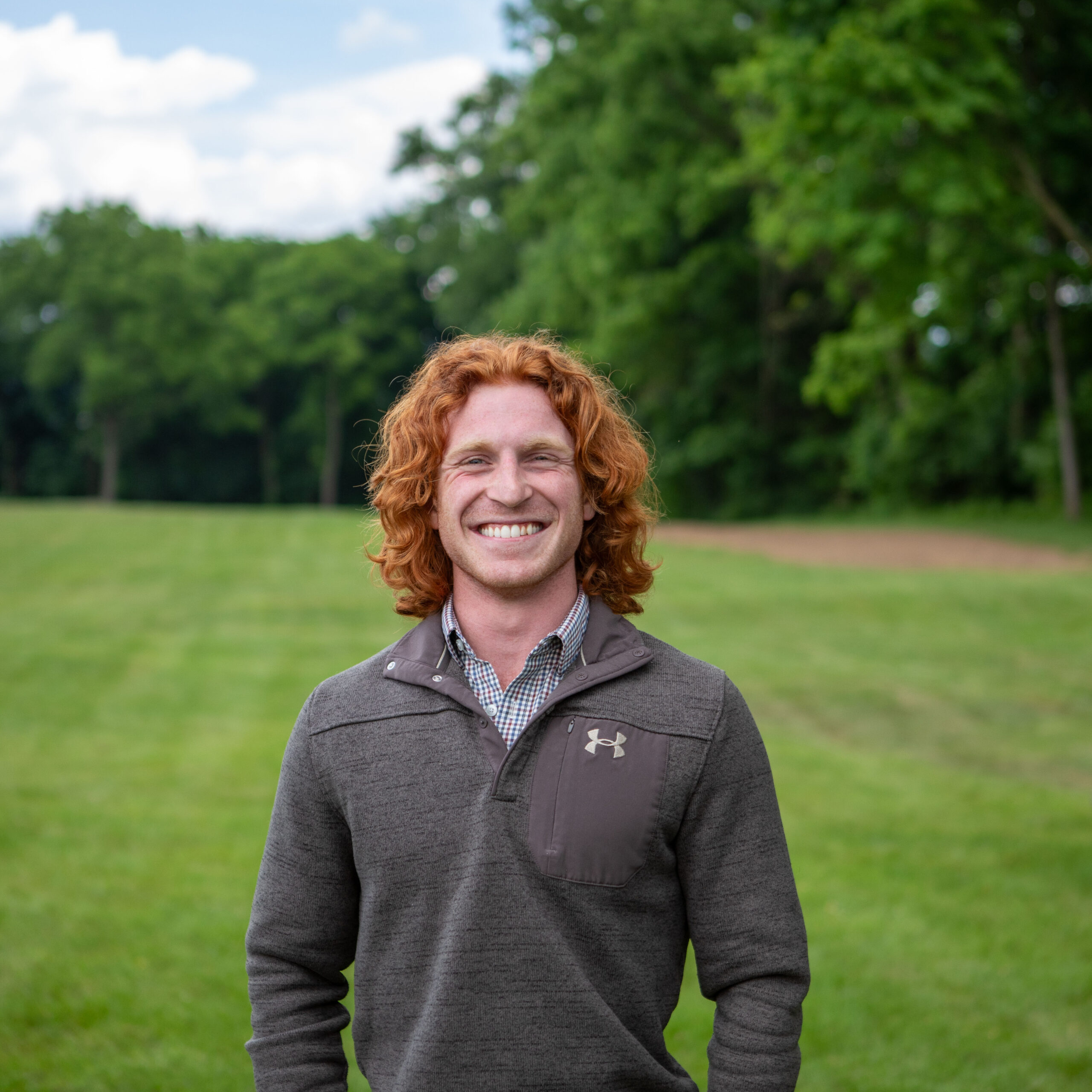 A photo of Jake the intern standing outside in a sunny field