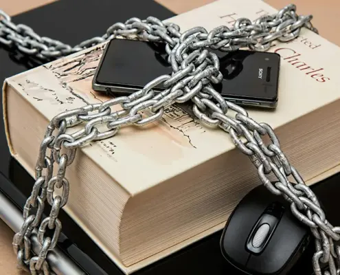 A laptop, book, and phone chained together to symbolize intellectual property protection